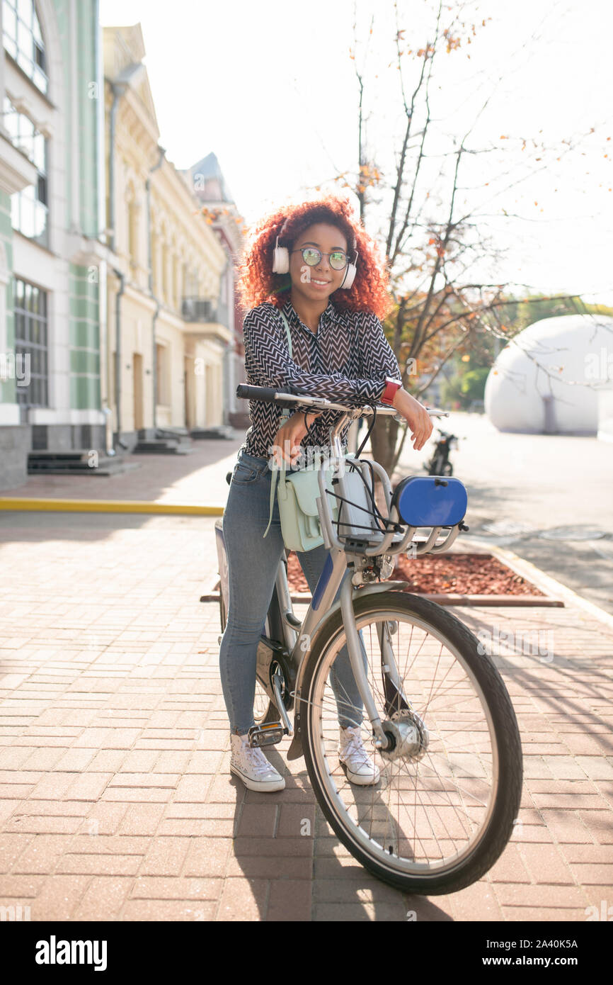 Curly girl in der Nähe von Bike auf dem Weg zur Universität Stockfoto