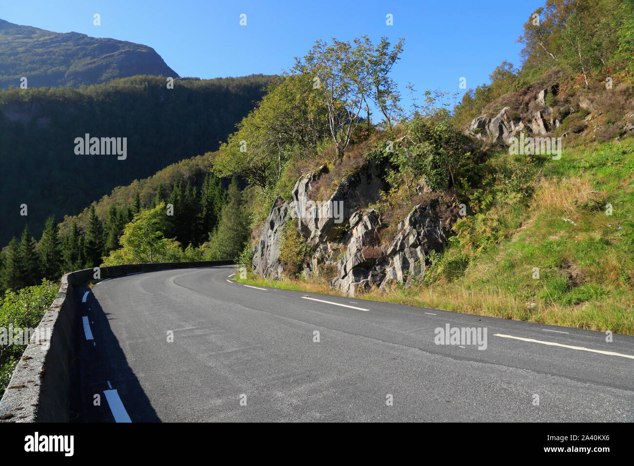 Eine geteerte Landstraße verläuft durch die ländliche Landschaft auf der Insel Osterøy im Kreis Vestland, Norwegen. Stockfoto