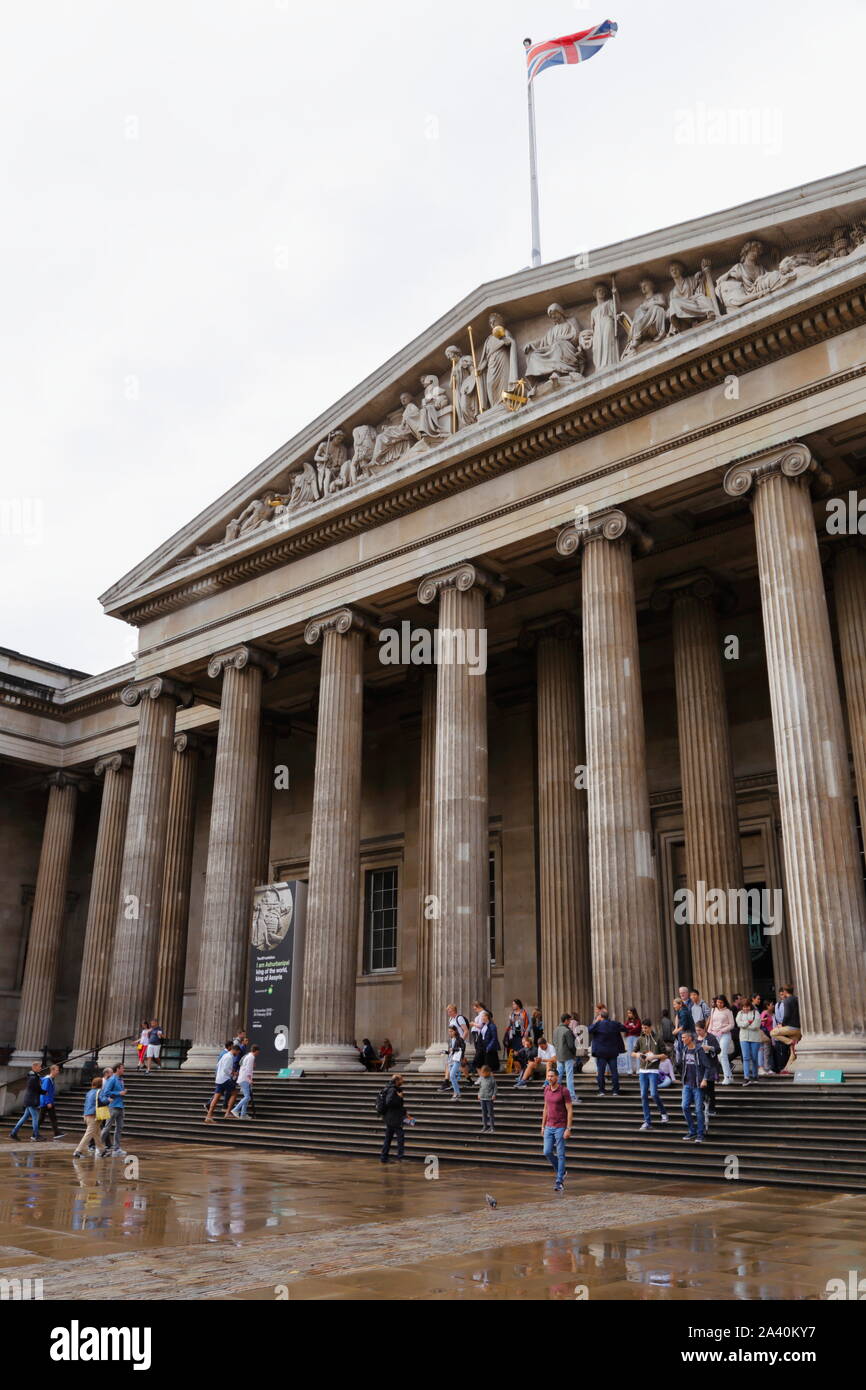 Die Fassade und Vorplatz des British Museum in London, Vereinigtes Königreich. Besucher Verlassen und Betreten der Haupteingang an einem verregneten Sommer. Stockfoto