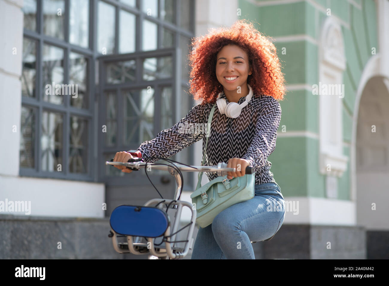 Strahlende lockiges Mädchen lächelnd beim Reiten Fahrrad am Wochenende Stockfoto