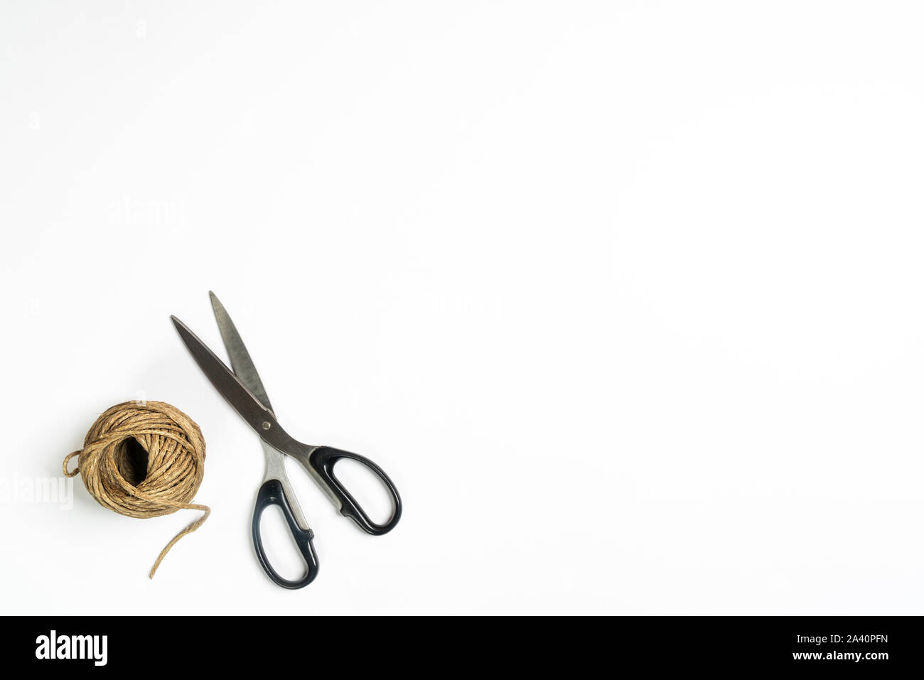 Eine Kugel von string und eine Schere auf eine weiße Fläche Stockfoto