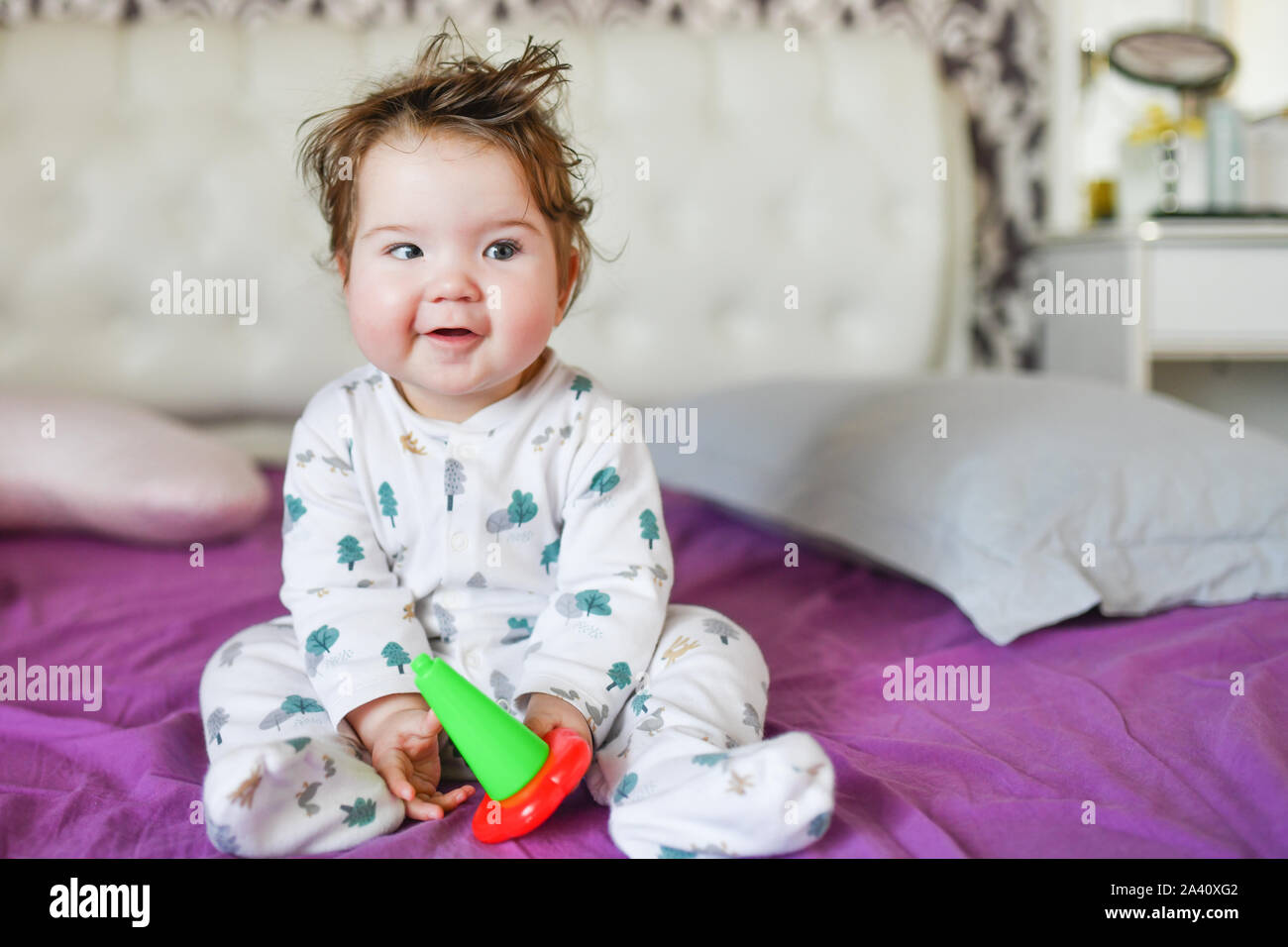 Baby auf Kamera posiert auf dem Bett zu sitzen. Das Kind spielt in Betten. Stockfoto