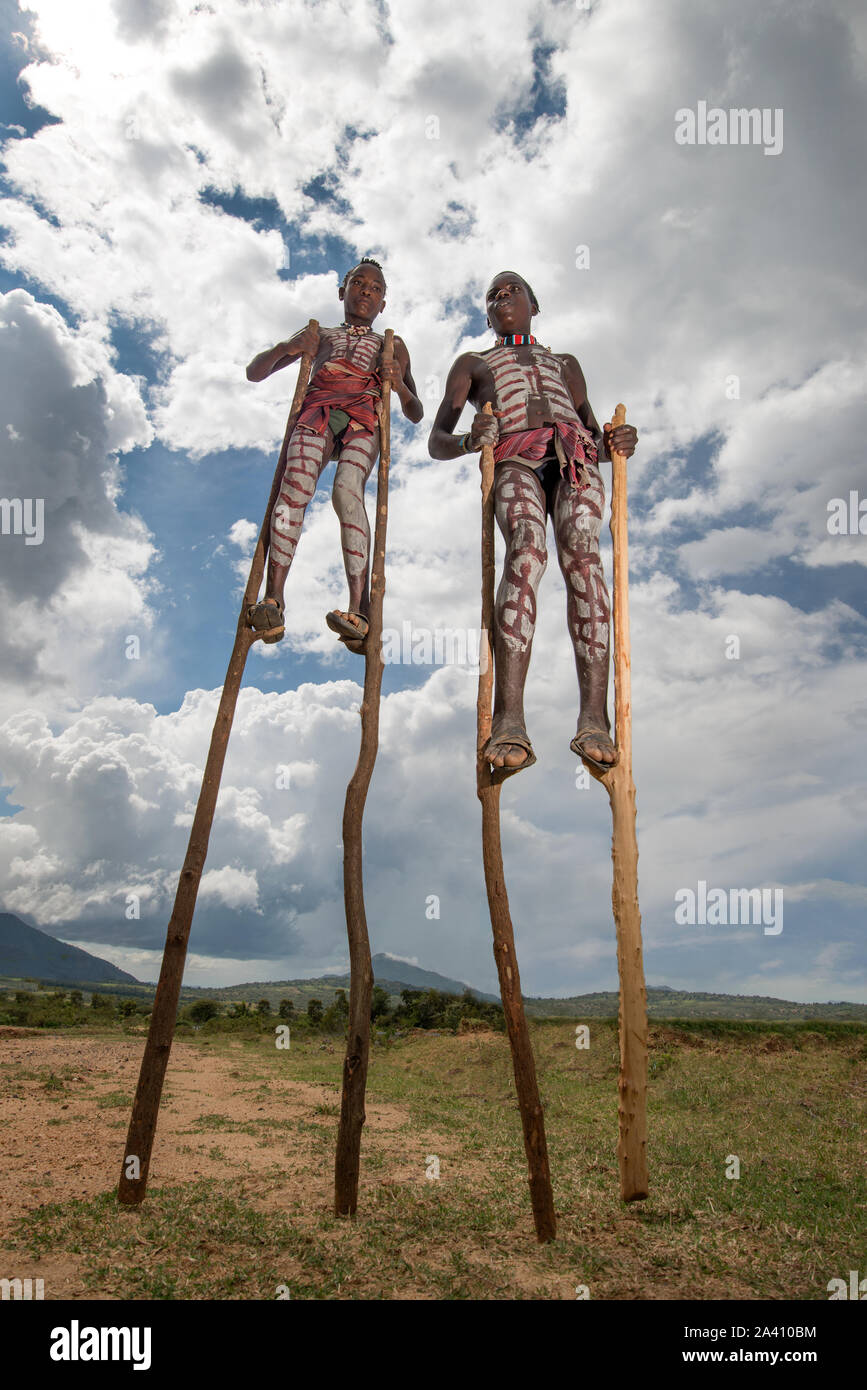Äthiopien: Zwei Jungen auf Stelzen - vielleicht eine geniale Art und Weise zu entkommen, die Schlangen in der Nähe? Schockierende Bilder zeigen die seltsamen Sitten der Stämme in Stockfoto