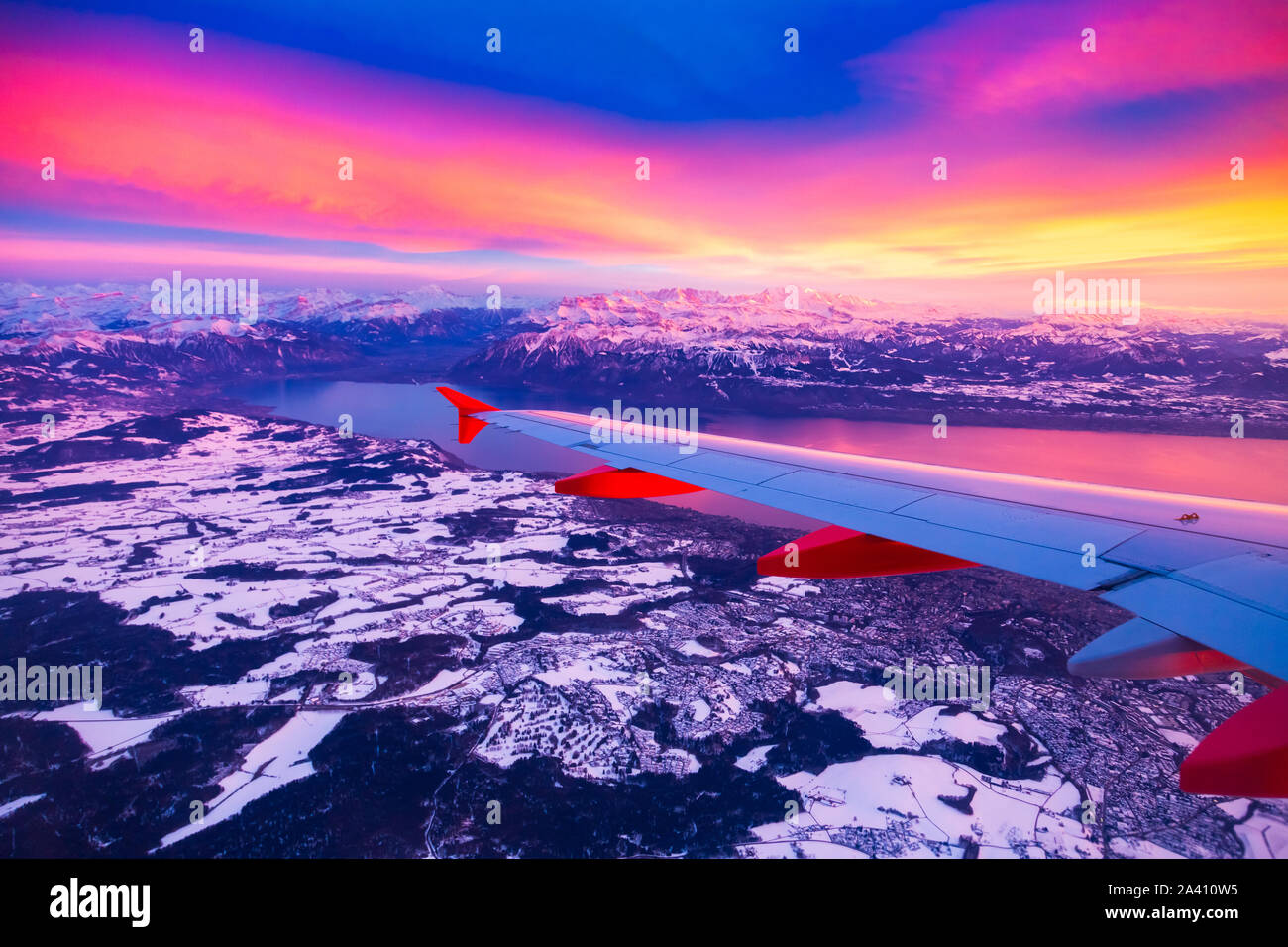 Blick aus dem Flugzeug Fenster während der Sonnenuntergang über den Bergen in der Schweiz Stockfoto