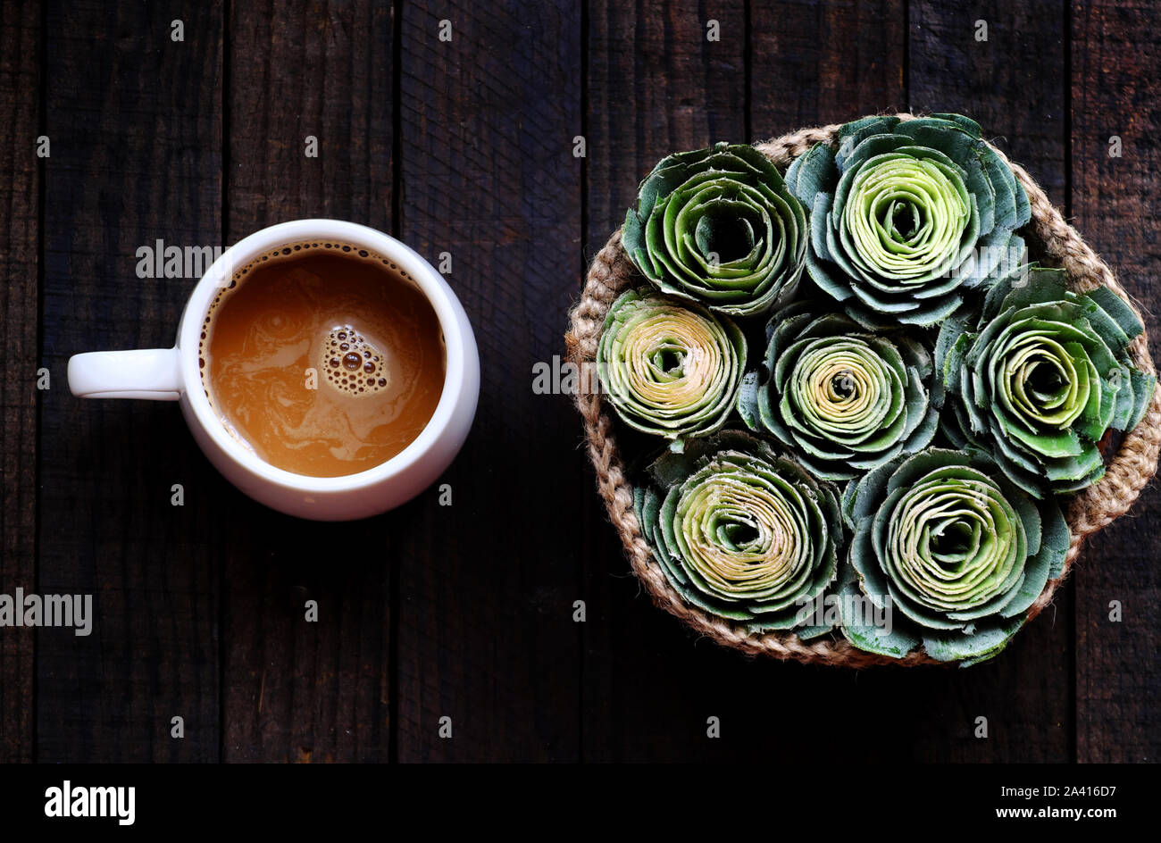 Ansicht von oben weiß Kaffeetasse mit Korb der Grüne Rose für Kaffee am Morgen Zeit zu Hause auf schwarzem Holz- Hintergrund Stockfoto