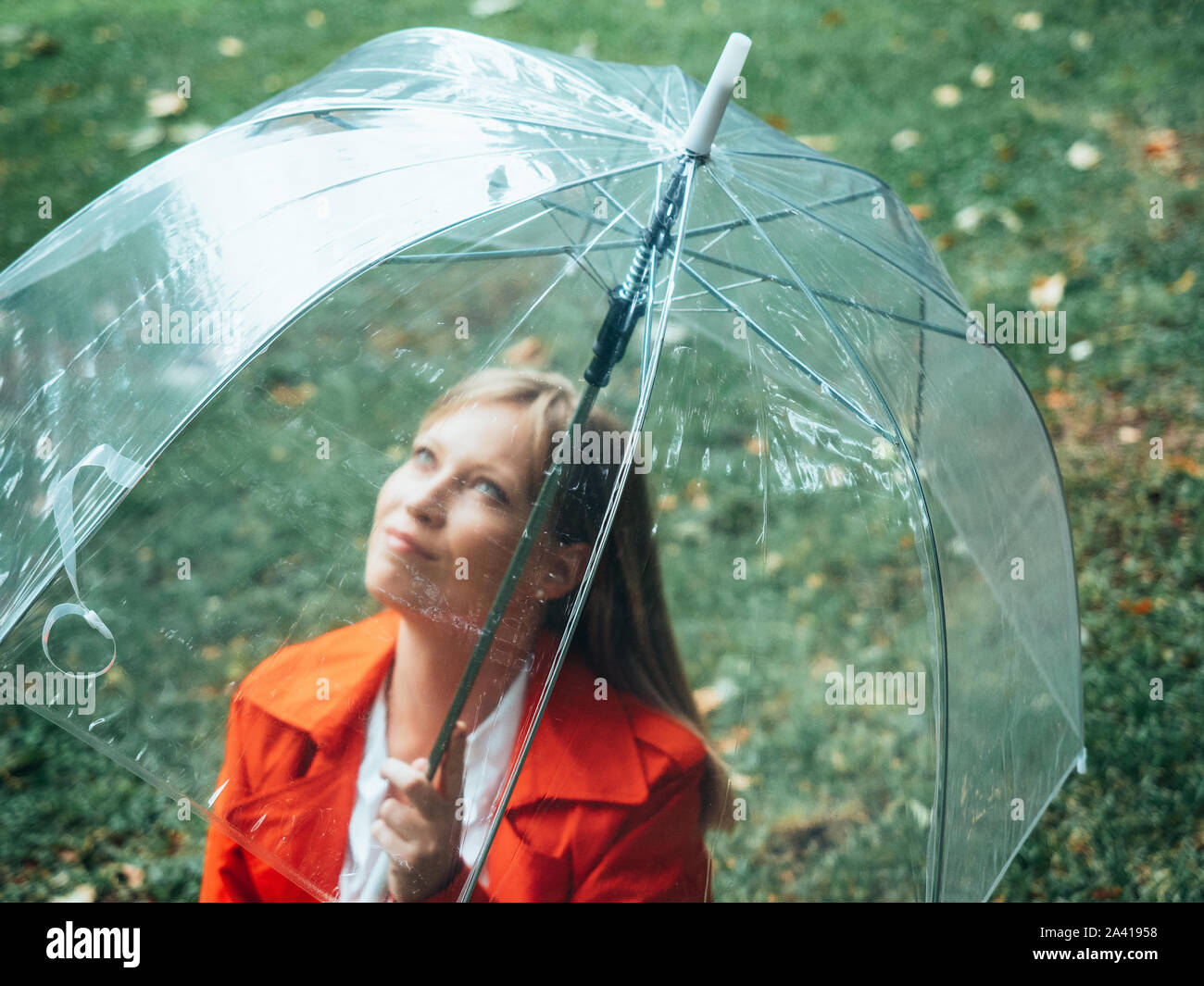 Kaukasische Mädchen mit roter gabardine Wanderungen durch den Park unter einem transparenten Dach. Stockfoto