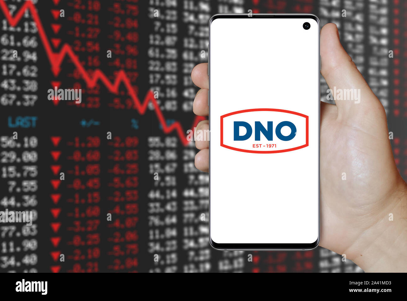Ein Mann hält ein Telefon mit dem Logo der Firma DNO auf der Osloer Börse gelistet. Negative Börse. Credit: PIXDUCE Stockfoto