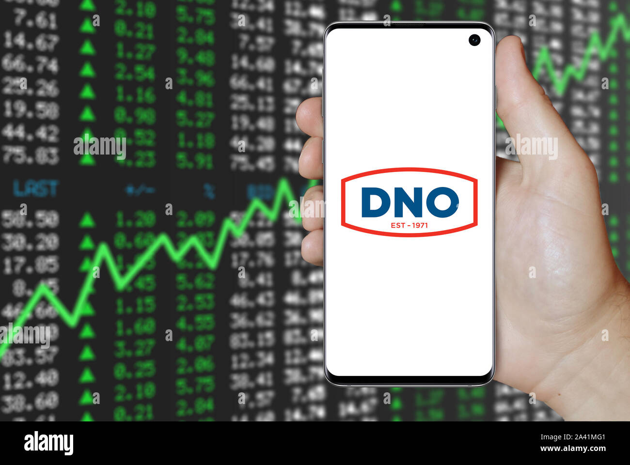 Ein Mann hält ein Telefon mit dem Logo der Firma DNO auf der Osloer Börse gelistet. Positive Börse. Credit: PIXDUCE Stockfoto