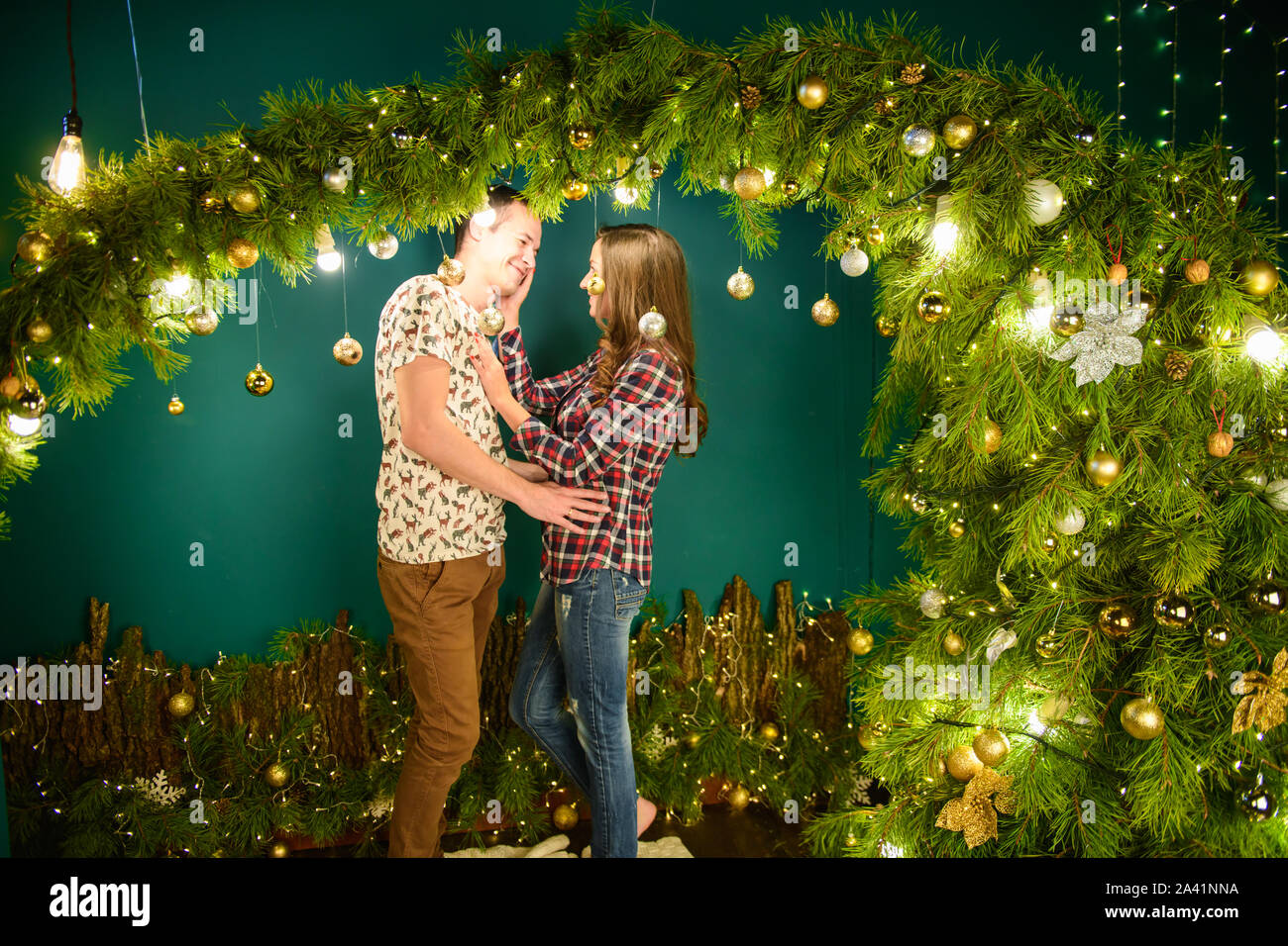 Verliebtes Paar in der Nähe von Weihnachten Hintergrund. Junges Paar Küssen in der Nähe der Weihnachtsbaum. Low Key. Silhouette Stockfoto