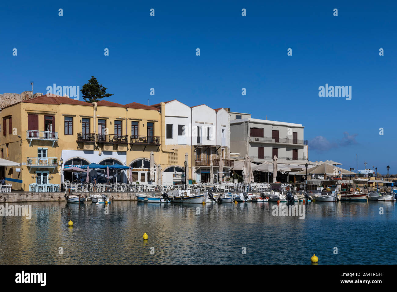 Venezianische Hafen mit kleinen Fischerbooten und Restaurants am Wasser in Rethymno, Kreta Stockfoto