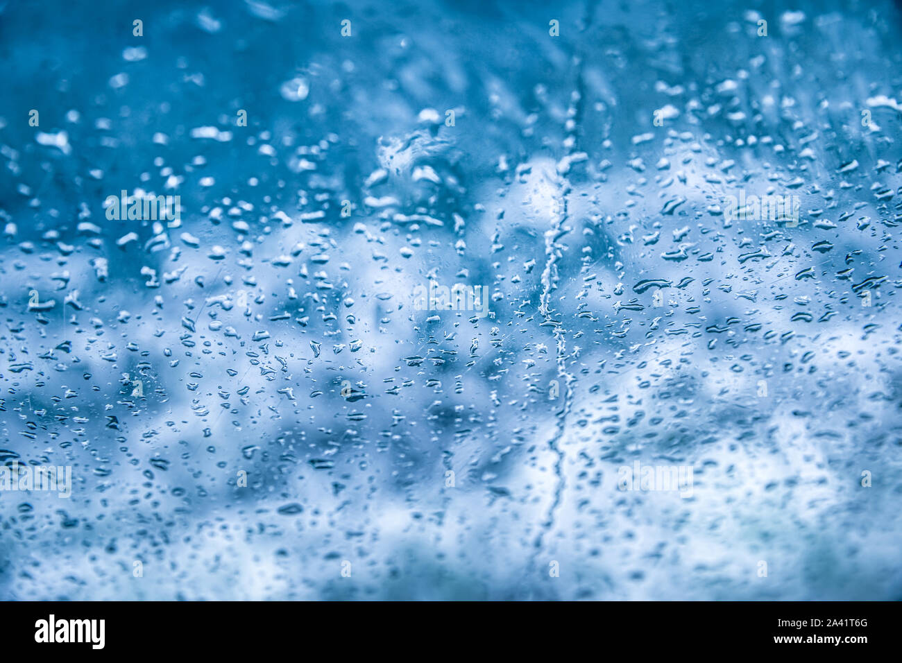 Wassertropfen fallen in den Glashintergrund. Stockfoto