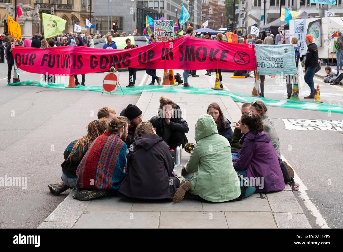 Jungen Demonstranten sitzen Diskussionen in einer Gruppe zu einem Aussterben Rebellion Straße Block an der Victoria Street, Westminster, London Stockfoto