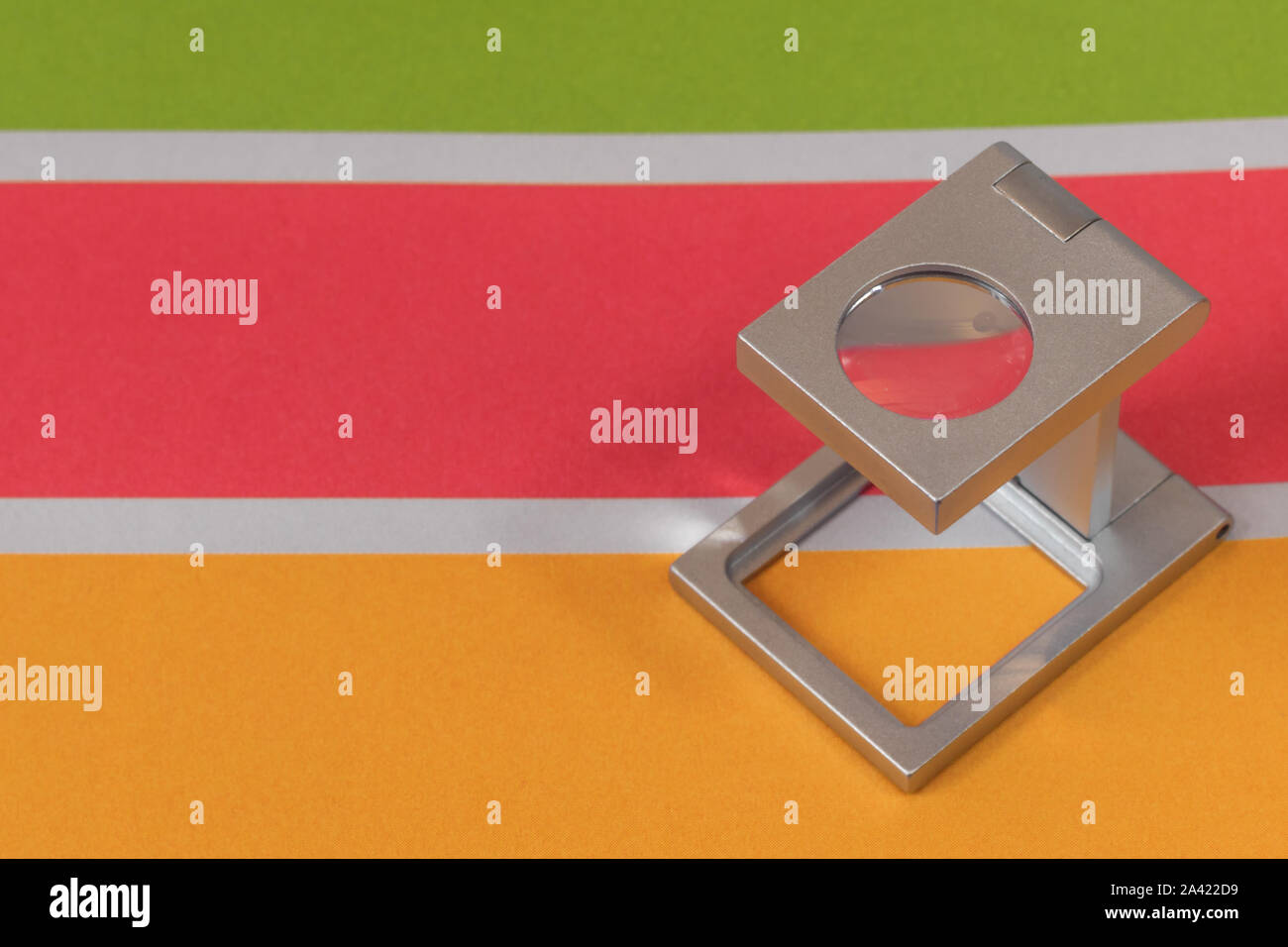 Silber Lupe stehend auf dem Testdruck, farbigen Hintergrund. Drucken Lupe auf Offset gedrucktes Blatt mit grundlegenden Farben- und Symbolleisten. Stockfoto