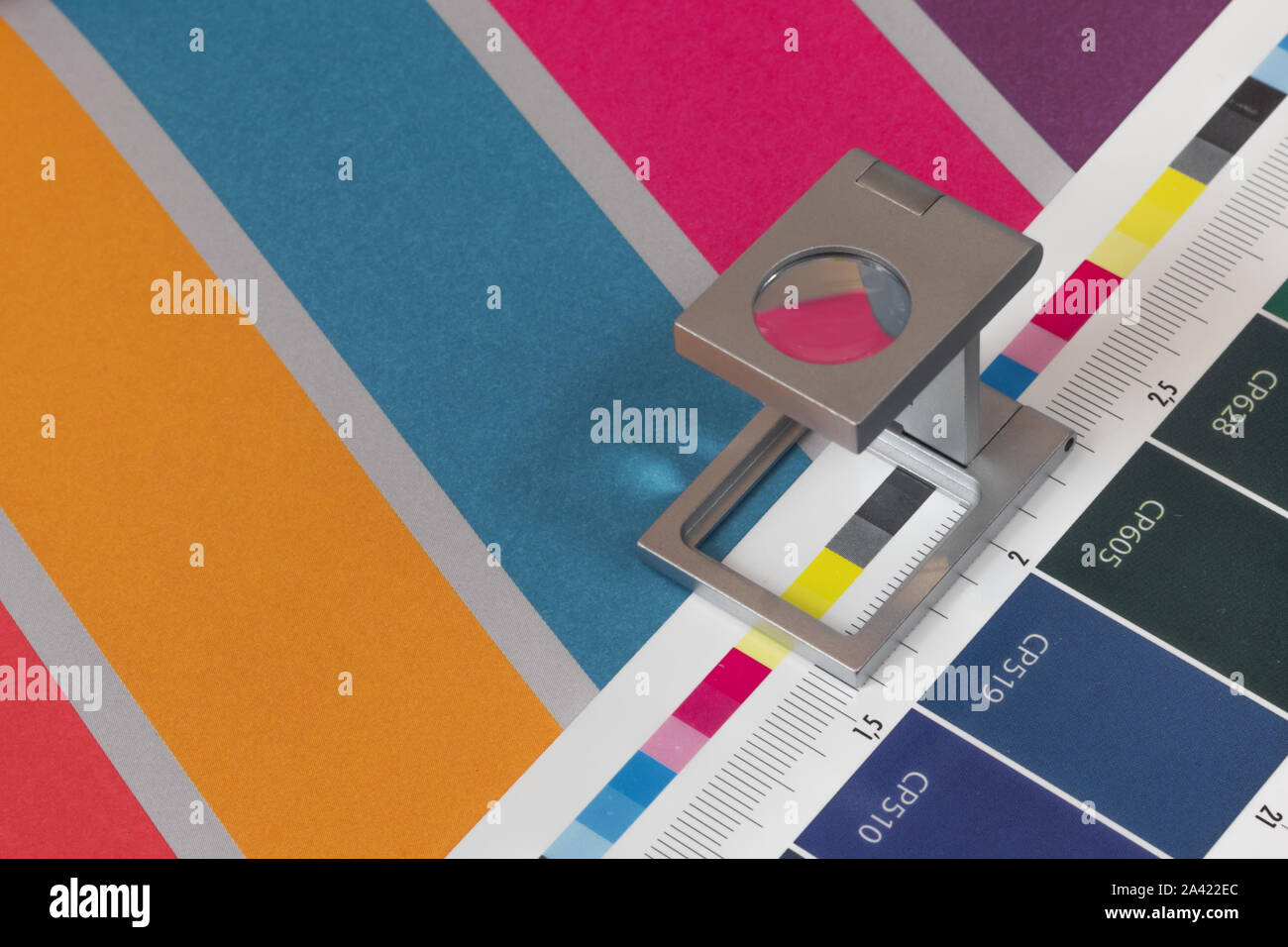Silber Lupe stehend auf dem Testdruck, farbigen Hintergrund. Drucken Lupe auf Offset gedrucktes Blatt mit grundlegenden Farben- und Symbolleisten. Stockfoto