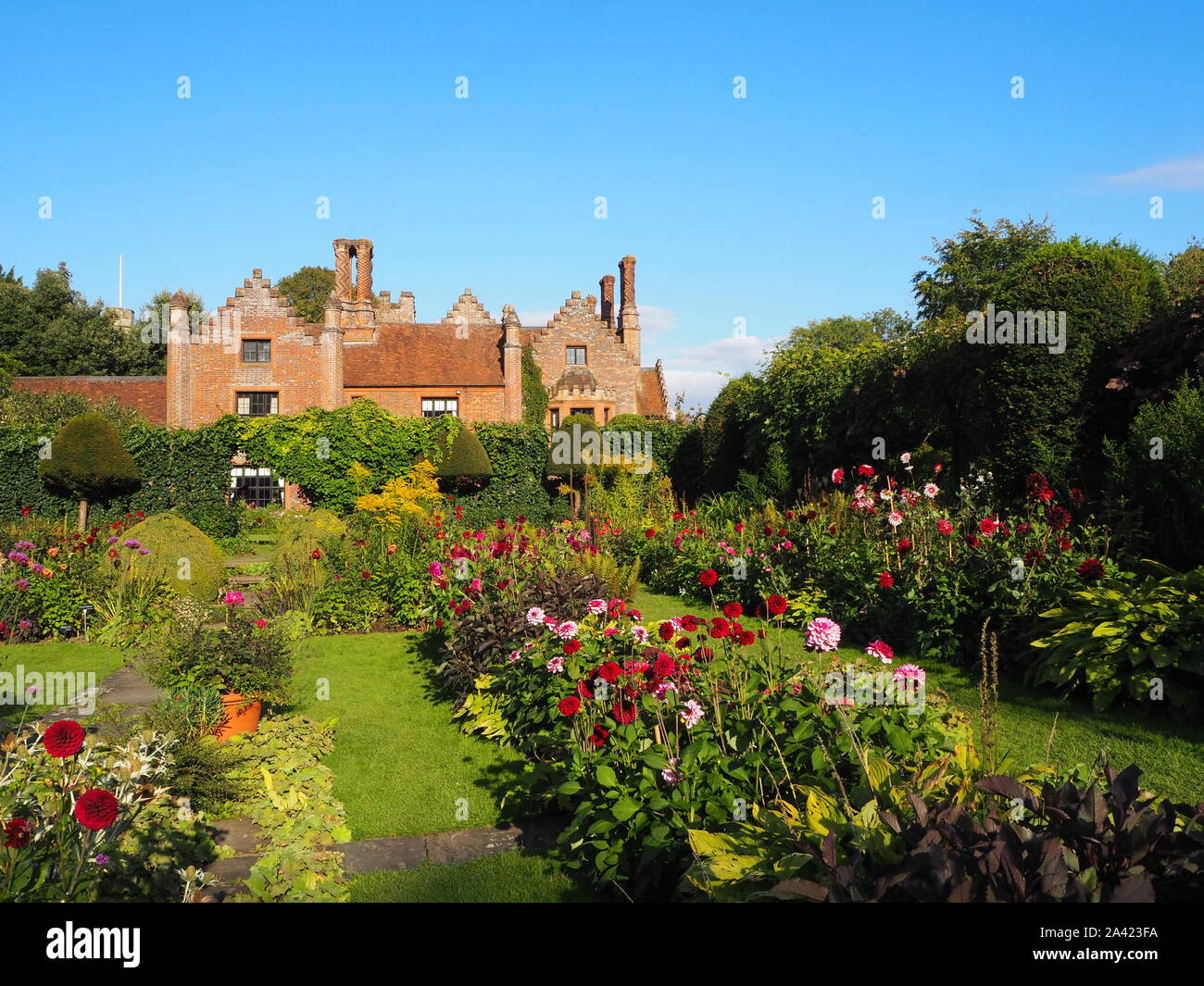 Chenies Manor House an einem Spätsommerabend, versunkene Garten Dahlien, Gras Pfade und Staudenbeet bei schönem Wetter.. Stockfoto