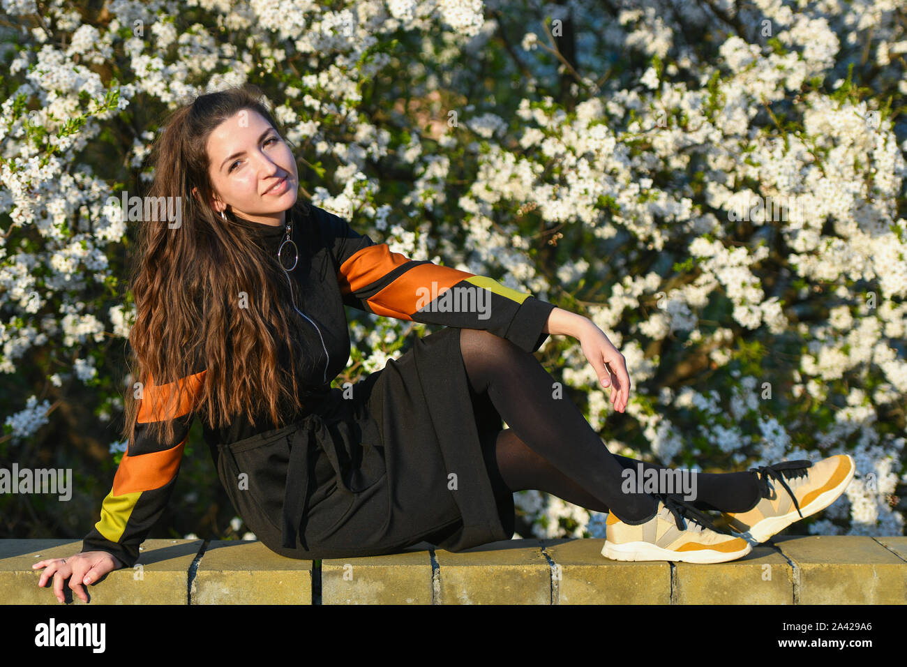 Mädchen auf dem Hintergrund einer weiß blühenden Baum. Outdoor Portrait von junge schöne Modisch elegante Dame mit langen Haaren, mit Strohhut Stockfoto