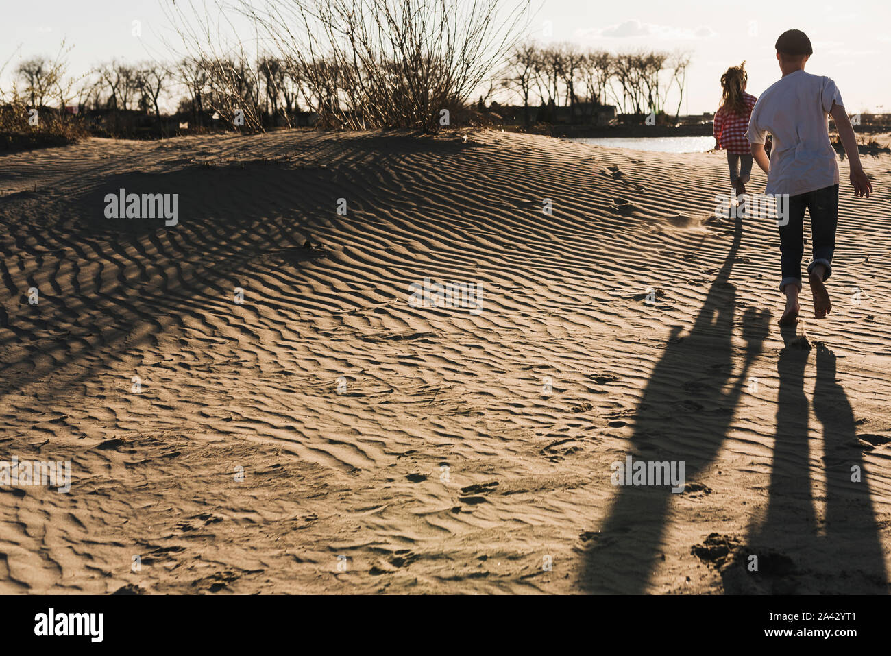 Kinder laufen über wellige Dünen am Fluss Stockfoto