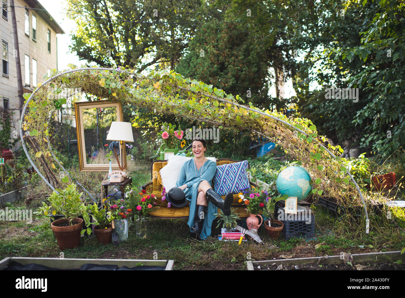 Glückliche Frau an einem vintage Couch in einem Garten Stockfoto