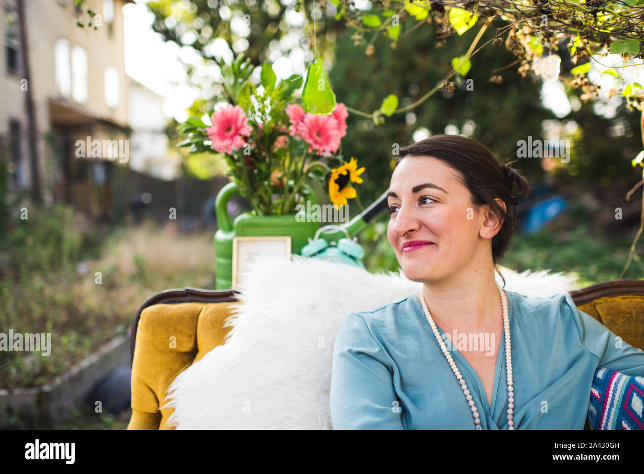 Lächelnde Frau mit Blumen im Freien auf einer Couch Stockfoto