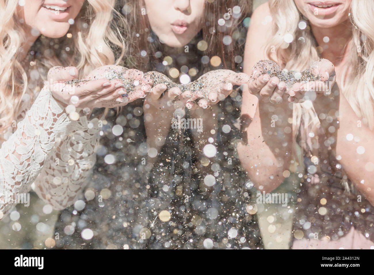 Drei junge Frauen blasen Glitter in der Hochschule Absolventenfeier Stockfoto