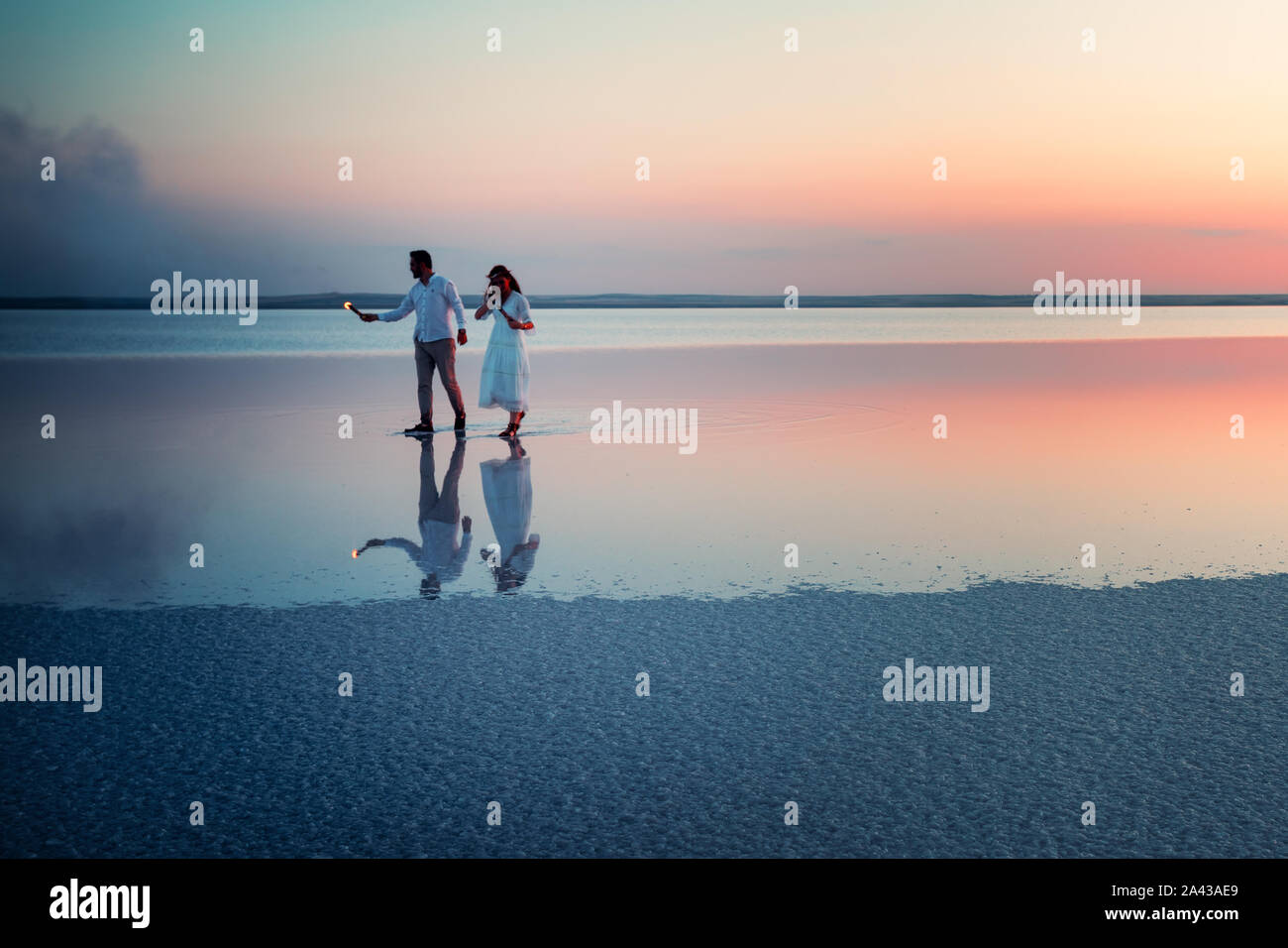 Brautpaar sind zu Fuß auf dem Wasser auf den Salzsee Tuz. Silhouetten von einem Mann mit Feuer in den Händen einer Frau. Symbol der Liebe. Sonnenuntergang. Provinz von A Stockfoto