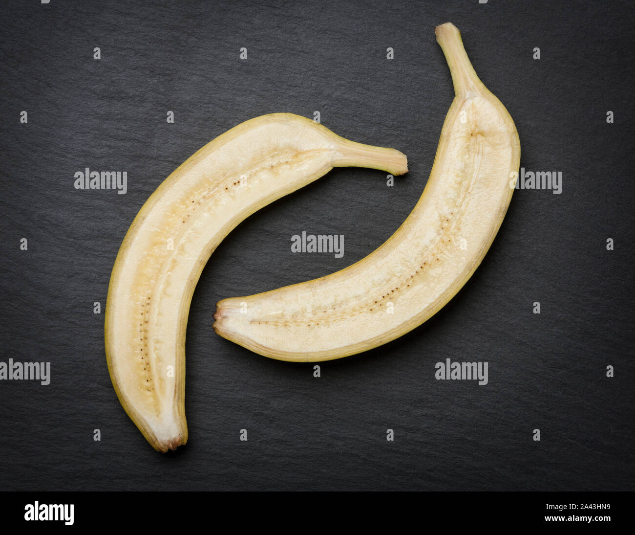 In der hälfte Banane auf dunkle Steinplatte. Stockfoto