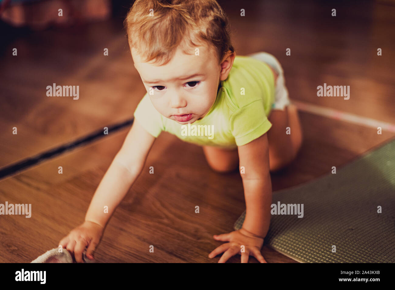 Baby Mädchen mit einem hübschen Gesicht krabbeln auf dem Holzboden ihres Hauses, retro Tönen und blasse Farben. Stockfoto