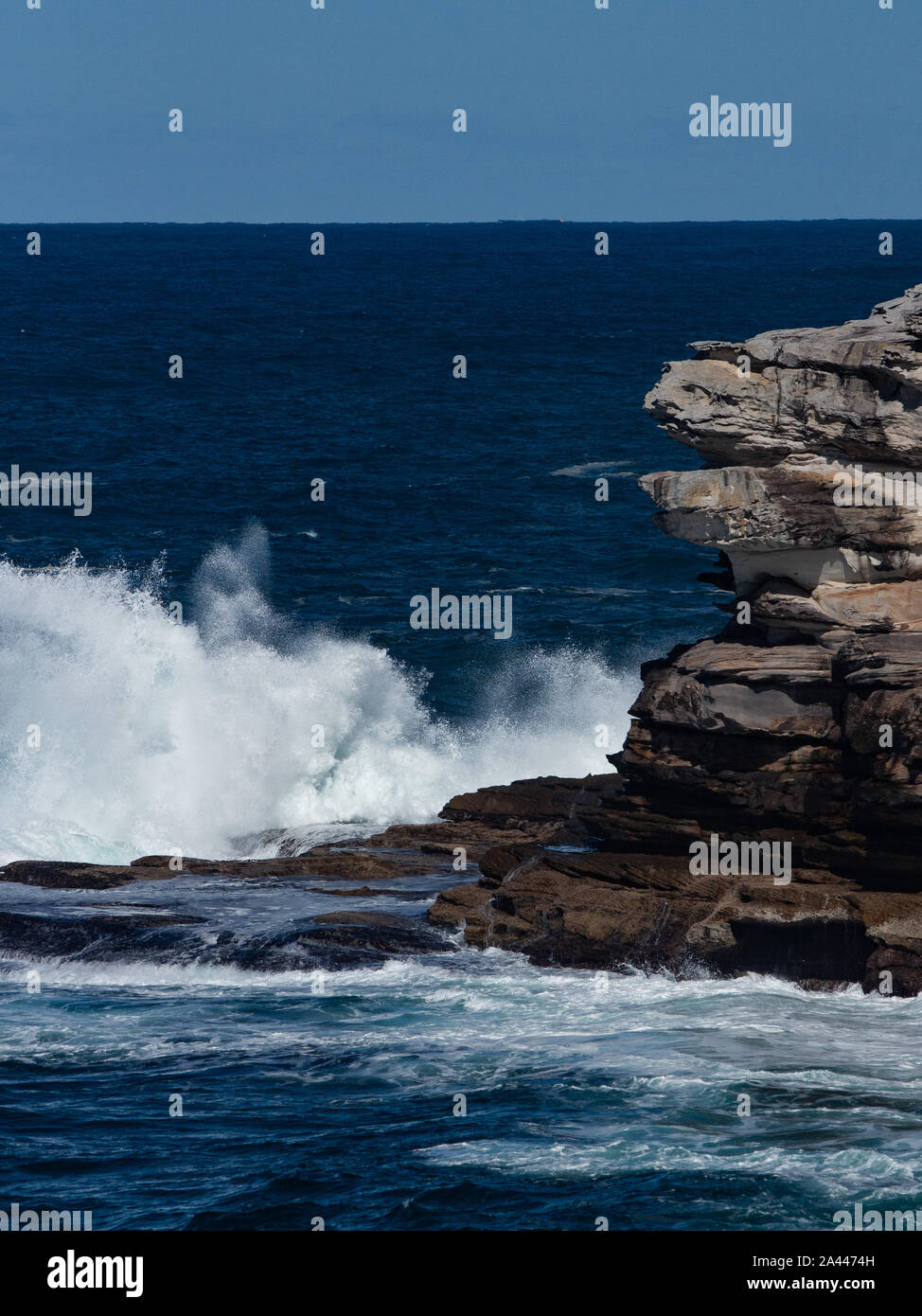 Oceanside rocky Sandsteinfelsen mit blauen Meer Wasser Wellen erzeugen Whitewash gegen Küste und klaren Himmel im Hintergrund Stockfoto