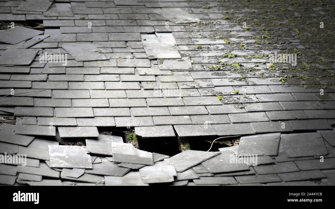 Zerbrochene Schieferplatten auf alten Moos bedeckt haus dach Stockfoto