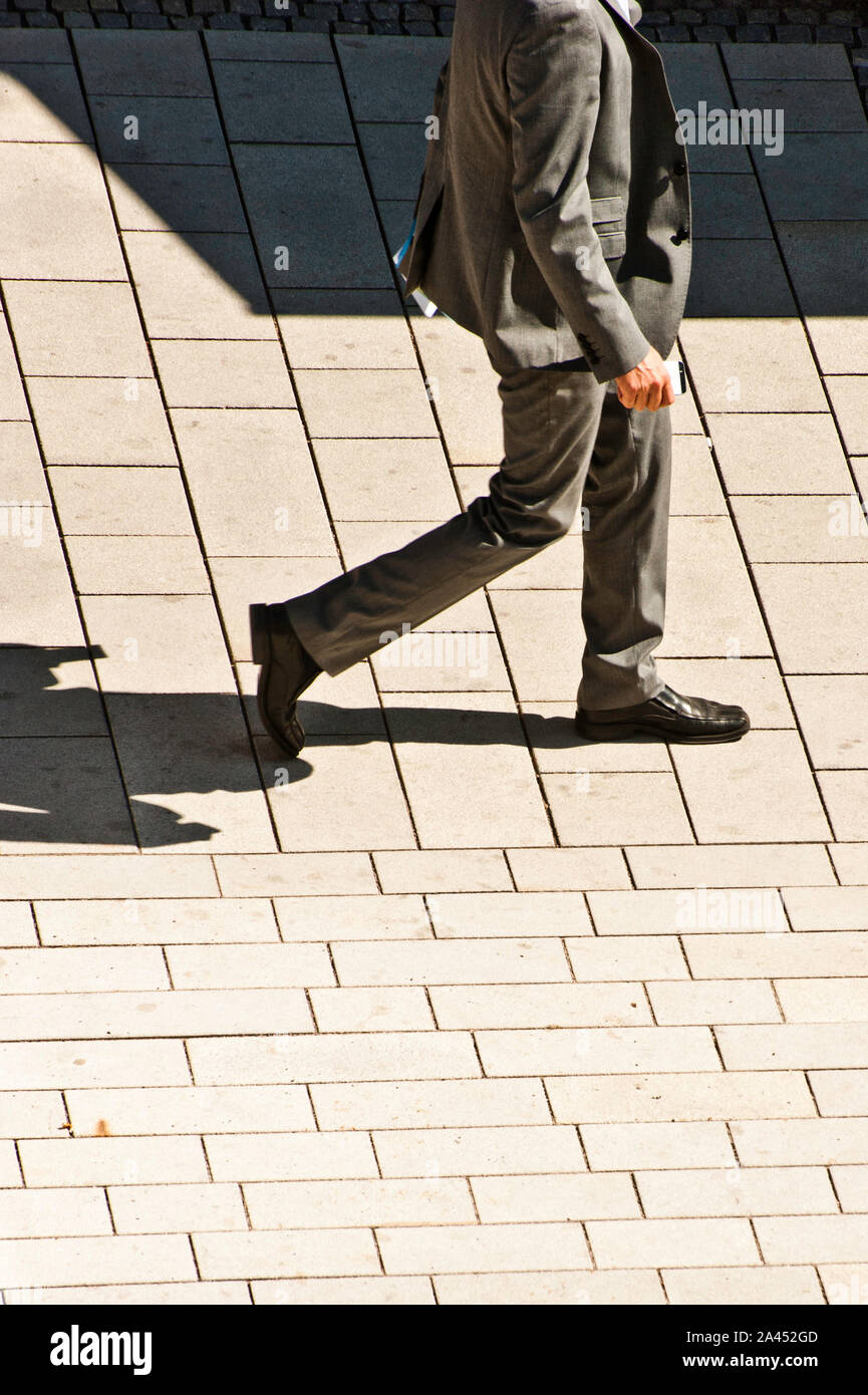 Mann in einem Anzug, der eine Straße entlang läuft Sonniger Tag Stockfoto