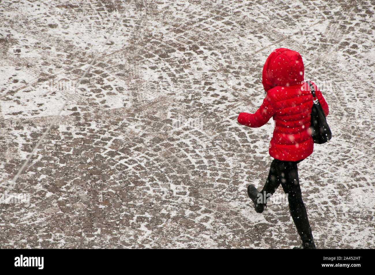 Frau trägt einen roten Mantel mit Kapuze gehen unter Schnee, gesehen von oben Stockfoto