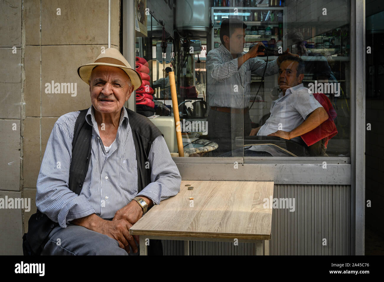 Mann an einem Tisch vor einem Friseur, Istanbul, Türkei. 10. Juni 2019 Stockfoto