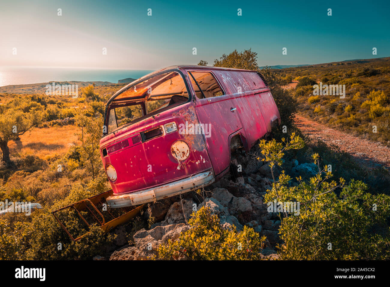 Abgebrochene van Bus auf den Felsen in der Mitte von Nirgendwo an einem sonnigen Tag. Meer im Hintergrund. Stockfoto