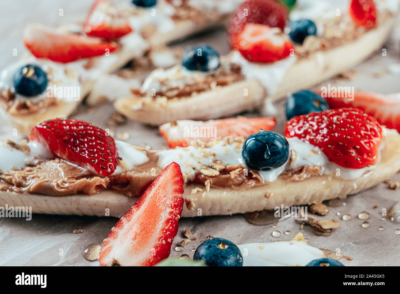 Banana Split mit Erdbeeren, Blaubeeren, Almond Butter und Honig Stockfoto