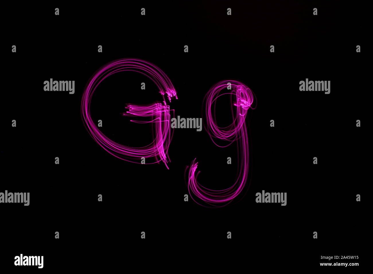 Lange Belichtung Foto des Buchstaben g im oberen und unteren Fall in leuchtenden Rosa Farbe Licht vor einem schwarzen Hintergrund. Licht Malerei Fotografie. Stockfoto