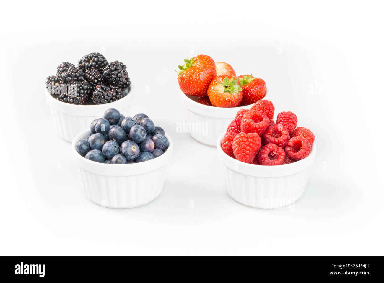 Blaubeeren, Himbeeren, Erdbeeren und Brombeeren in förmchen vor weißem Hintergrund Stockfoto