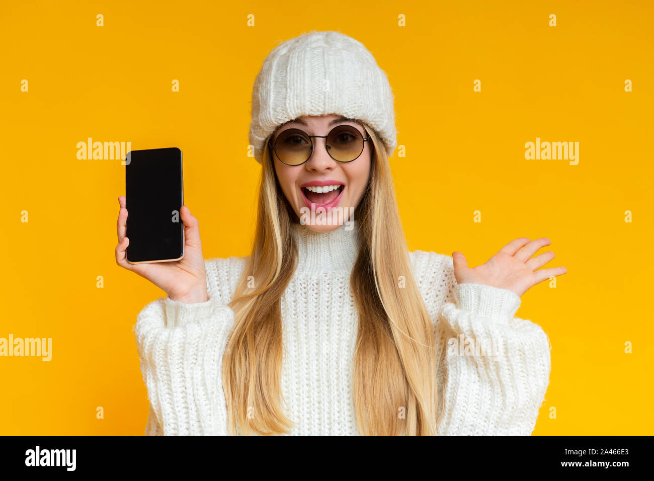Emotionale Frau im Winter hat zeigt leeren Bildschirm des Smartphones Stockfoto