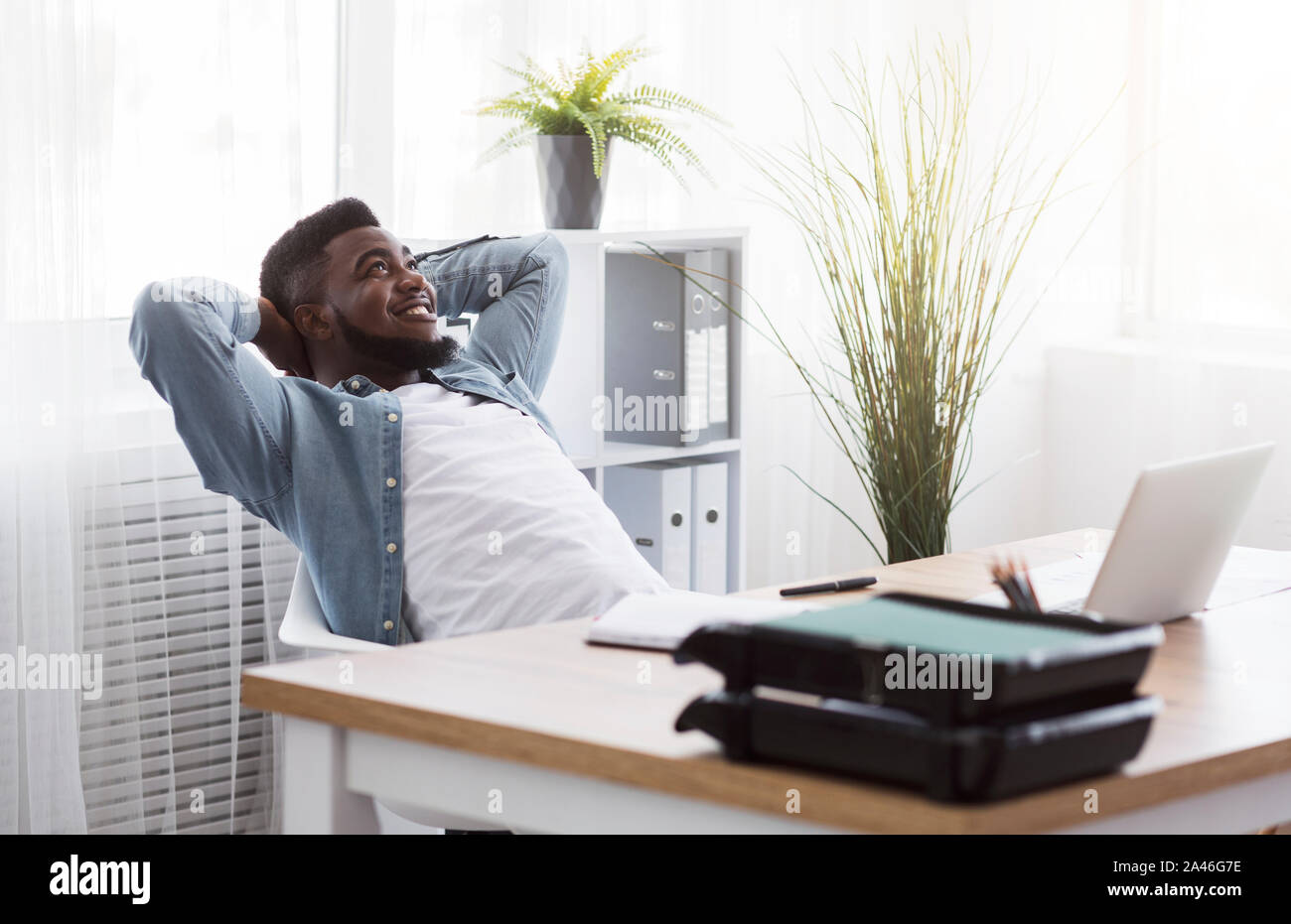 Freundliche Mitarbeiter lehnte sich zurück auf Stuhl mit Hände hinter den Kopf Stockfoto