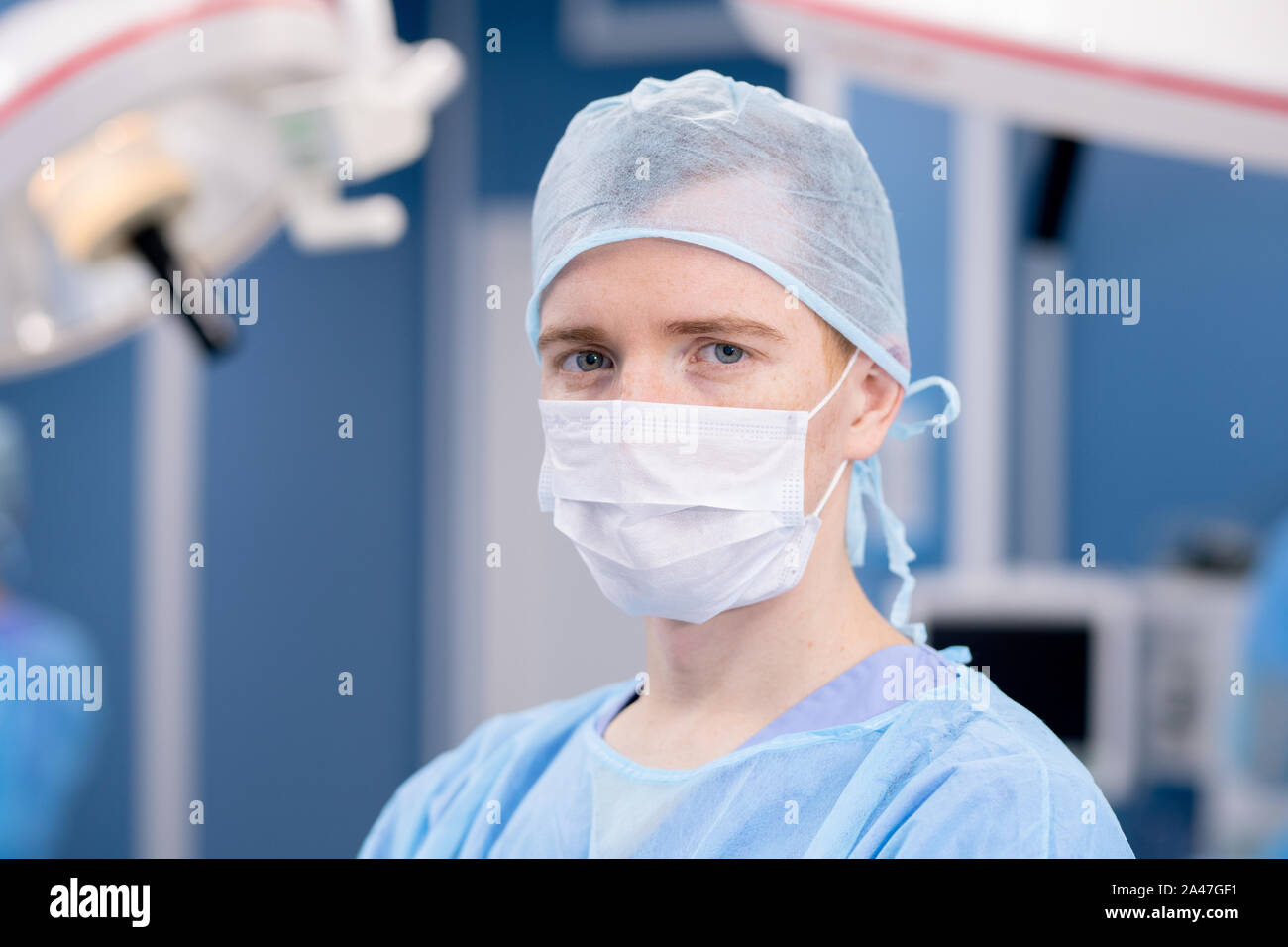 Junge Praktikantin oder Chirurg in Schutzmaske und einheitliche Blick auf Sie Stockfoto
