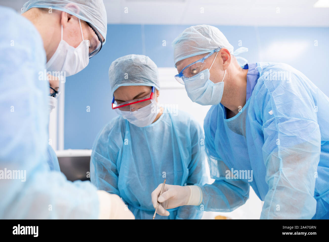 Gruppe von Chirurgen in Masken, Handschuhe und Arbeitskleidung Biegung über die Patienten Stockfoto