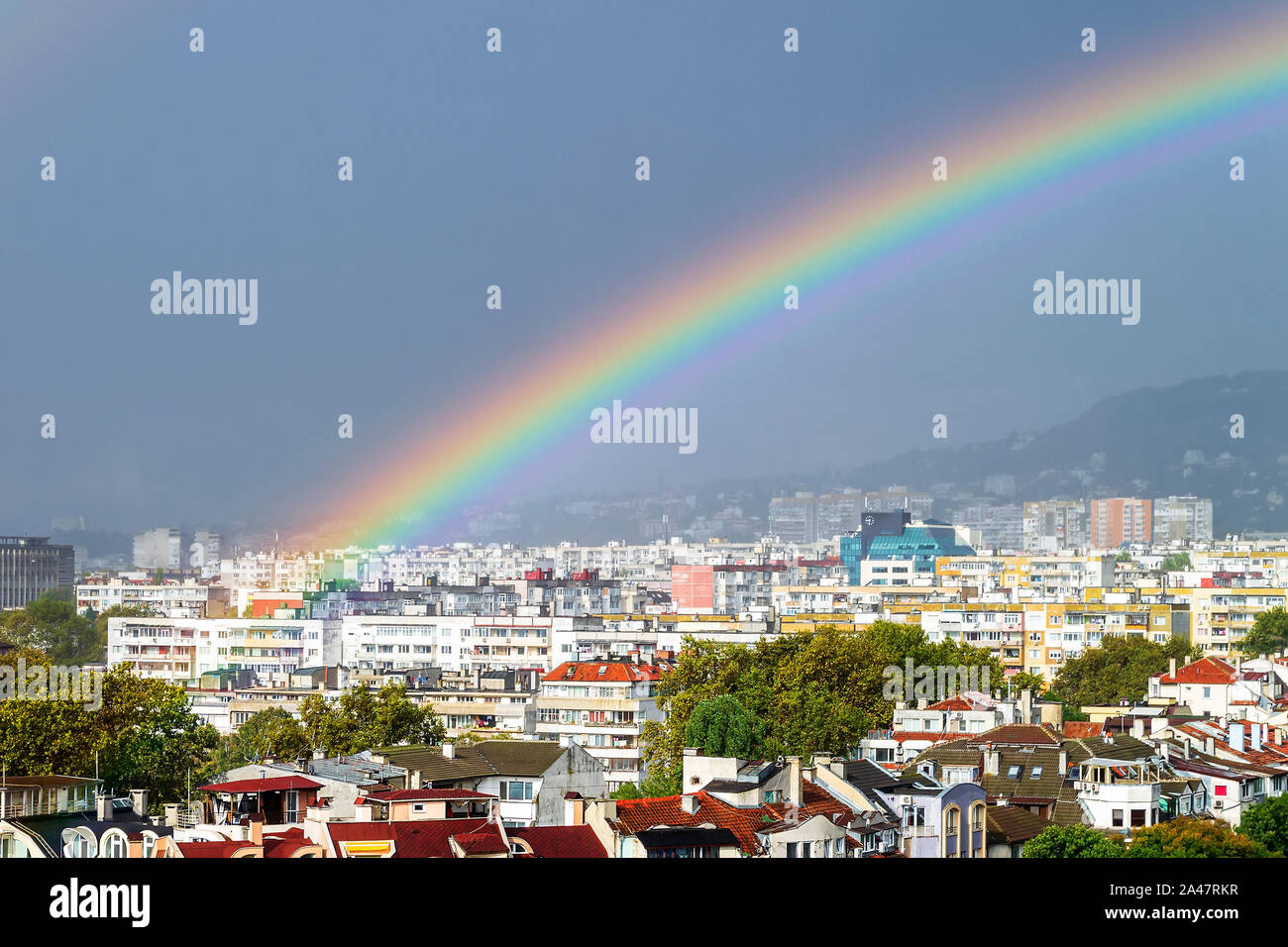 In der Nähe von wunderschönen Regenbogen über Wohngebiet der Stadt. Malerische Sommer Stadtbild mit einem Regenbogen. Schönheit in der Natur. Stockfoto