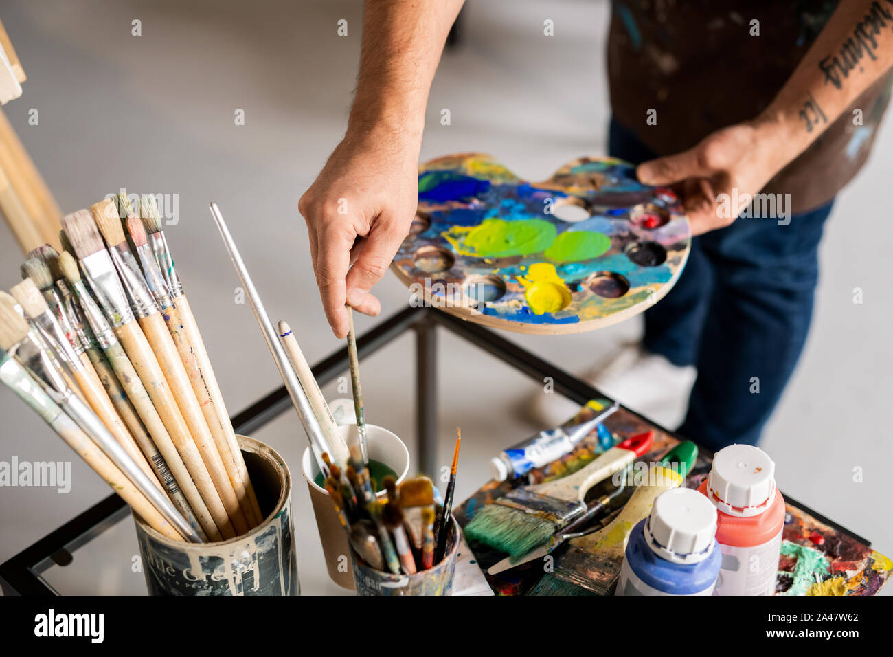 Maler holding Palette mit gemischten Farben und Pinsel in Wasser Stockfoto