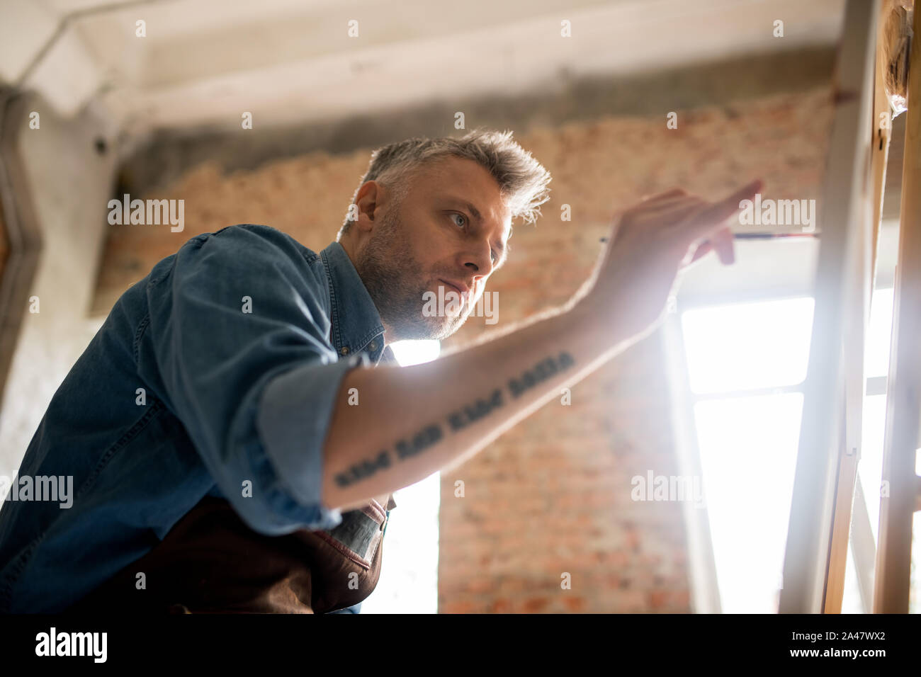 Ernst und aufmerksam Mitte - gealterte Maler über neue Malerei arbeiten Stockfoto