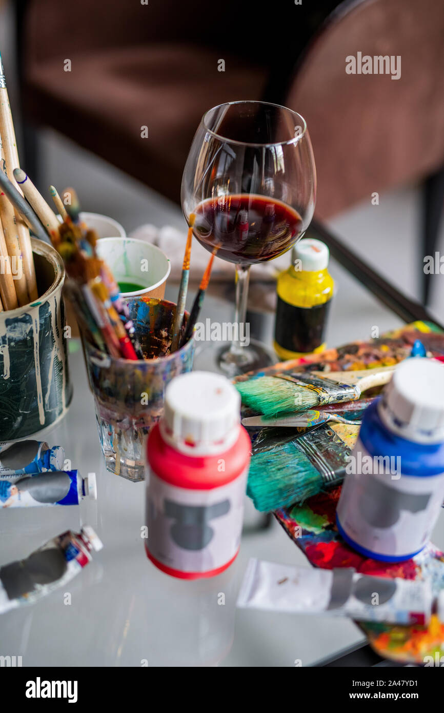 Glas Rotwein unter Pinsel und verschiedene Farben und Gouachen Stockfoto