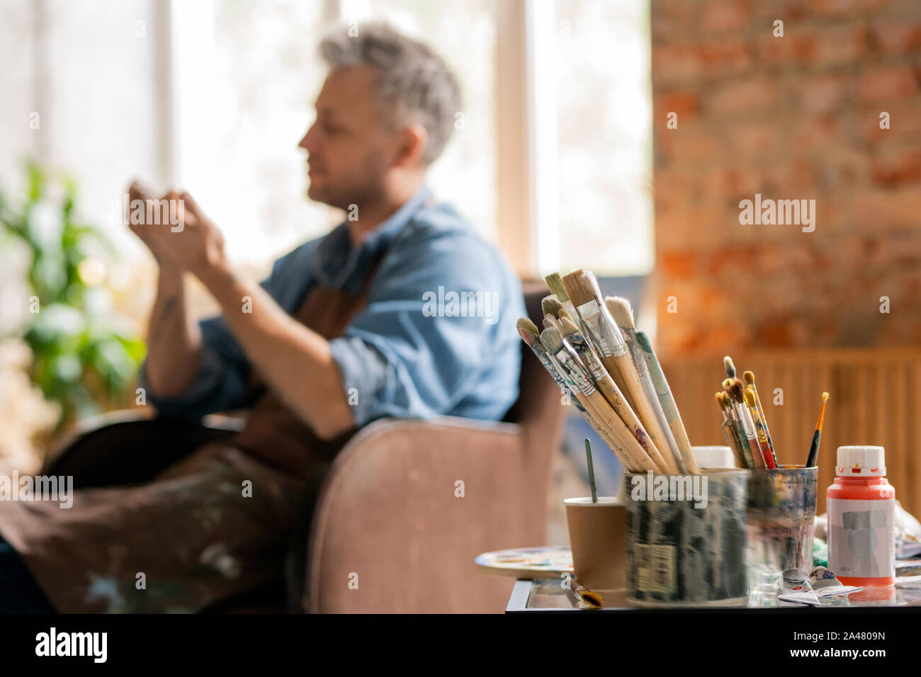 Zwei Trauben von Pinsel in schmutzigen Blechdosen und jar von Gouache auf Tabelle Stockfoto