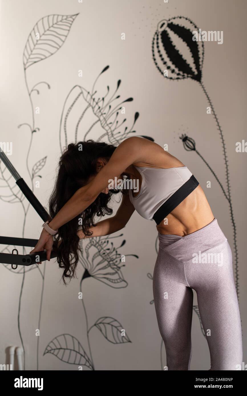 Editorial - Junge Pilates Instructor Frau Ausübung auf Peak Pilates Reformer. Mit einem Pilates Ring. Konzept für Pilates 09/2019 Stockfoto
