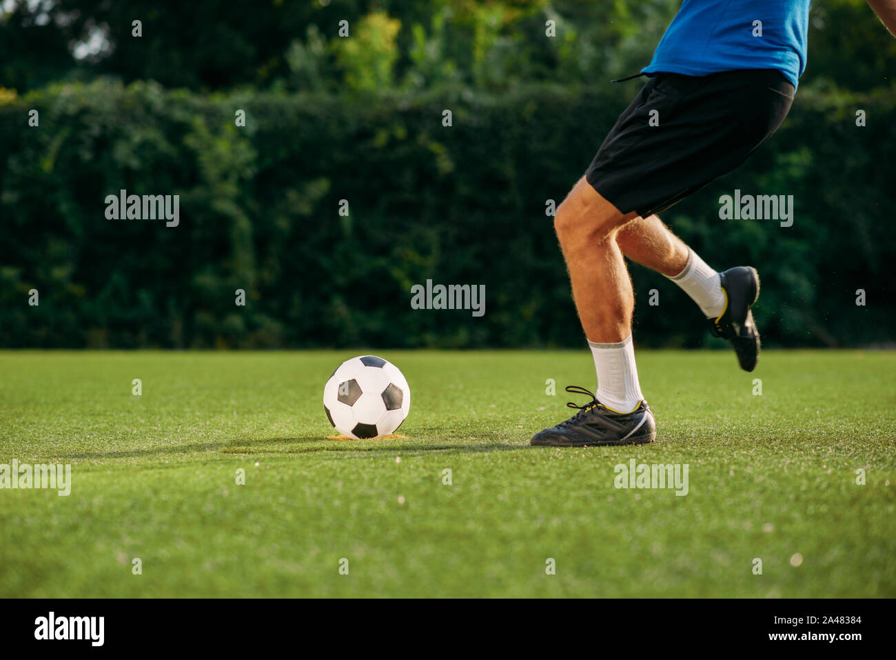 Männliche Fußballspieler schlägt die Kugel auf dem Feld Stockfoto