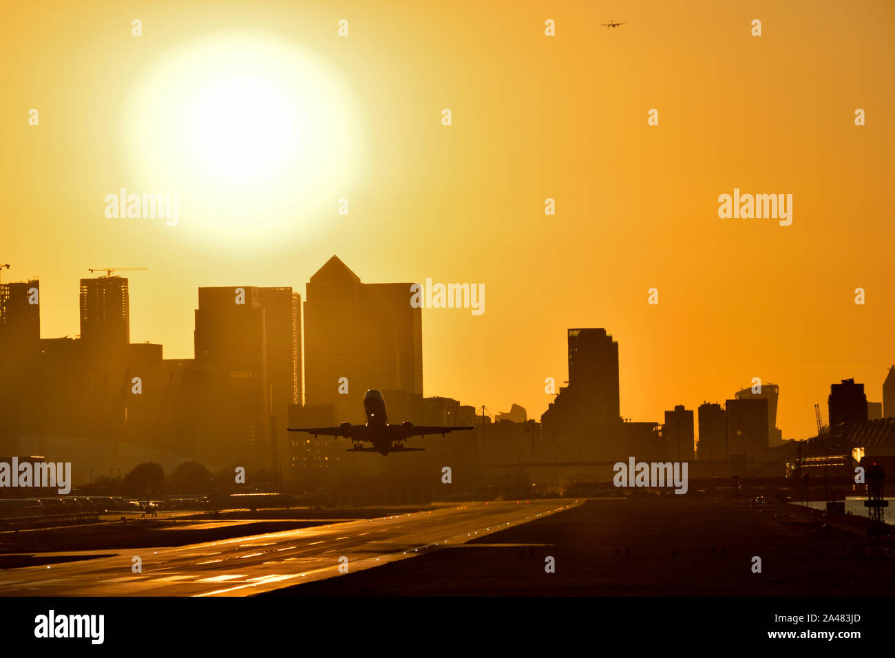 Flugzeug Vom Flughafen London City mit goldenen Himmel als die Sonne hinter den Canary Wharf skyline setzt Stockfoto