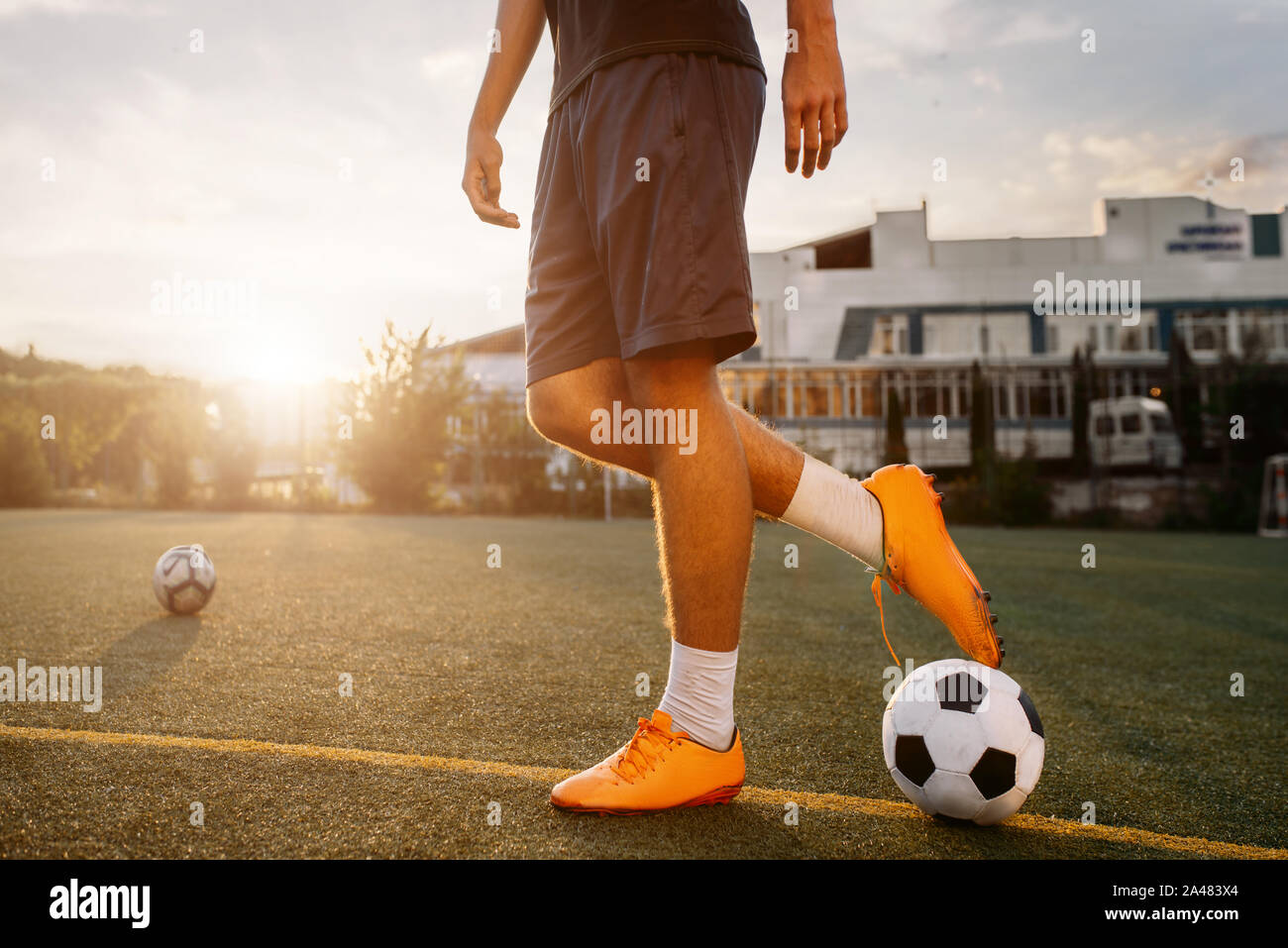 Fußball-Spieler mit Ball auf dem Feld bei Sonnenaufgang Stockfoto