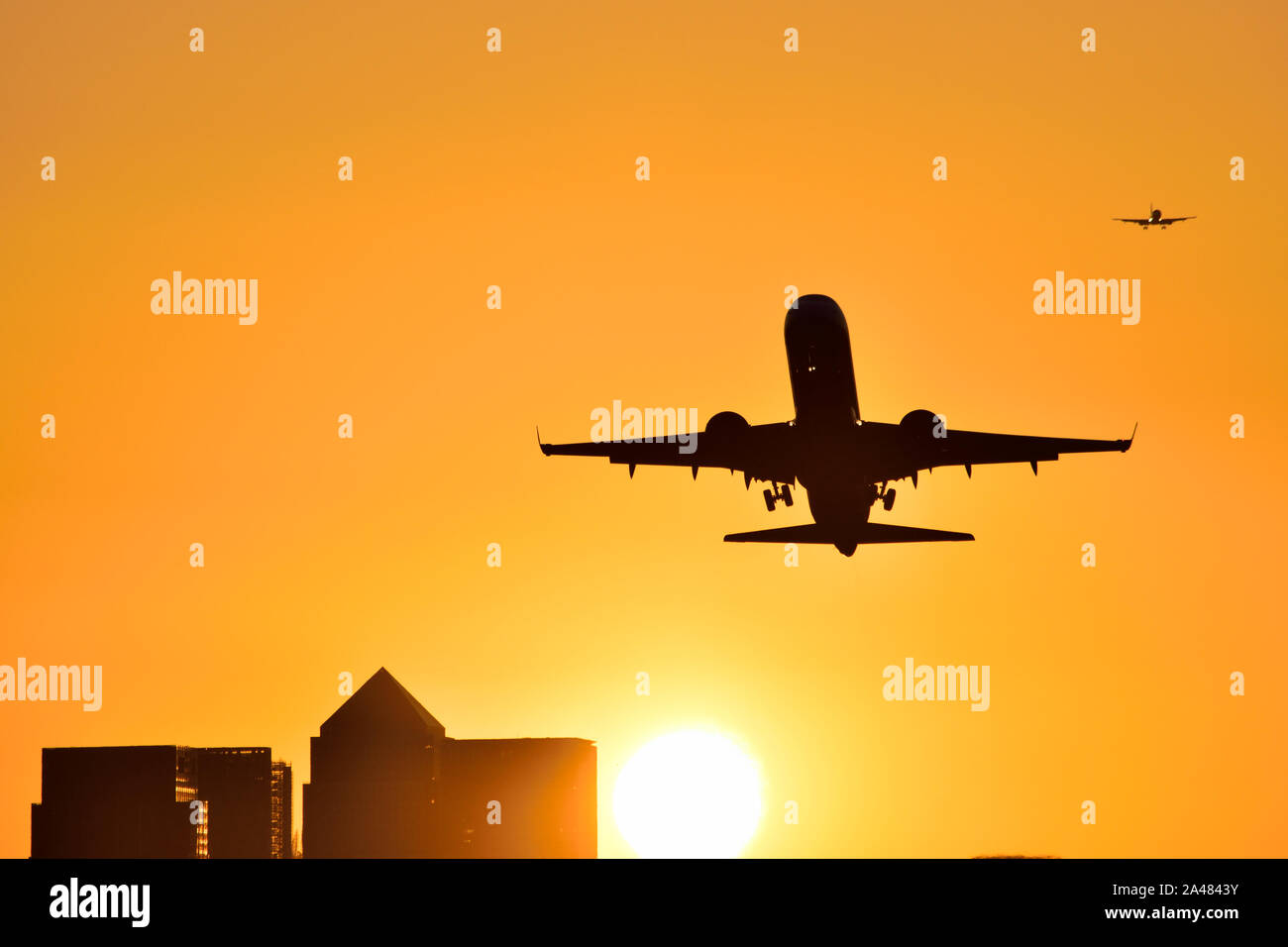 Flugzeug Vom Flughafen London City mit goldenen Himmel als die Sonne hinter den Canary Wharf skyline setzt Stockfoto